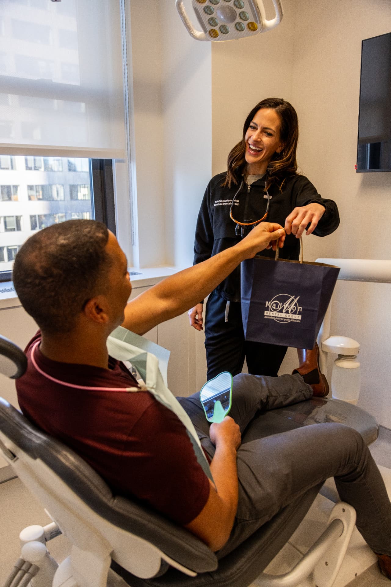 A Madison Dental Group doctor handing a patient a branded gift bag chairside